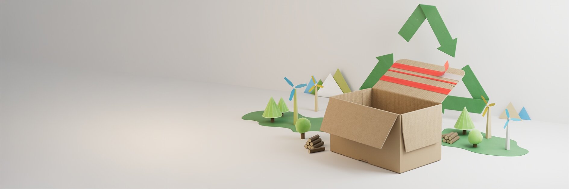 A cardboard box sits open on a white surface, sealed with tesa tape, with small models of trees, wind turbines, and logs behind it. A green recycling symbol is displayed on the wall in the background. (This text has been generated by AI)